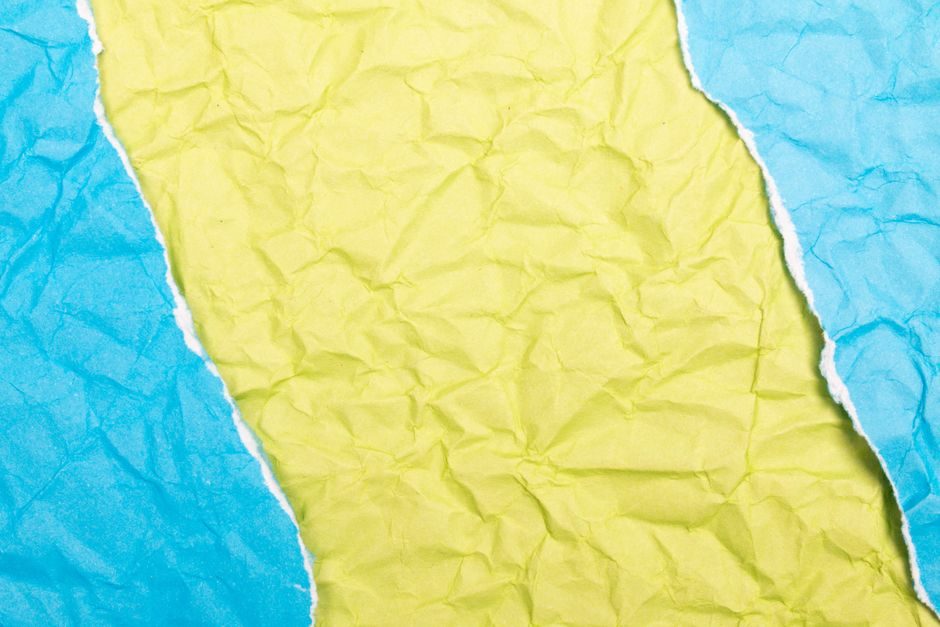半见 — Close-up of brightly colored torn crumpled paper creating a vibrant textured background.