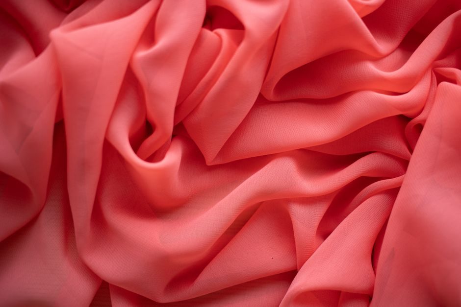 渥赭 — A close-up of elegant red fabric with gentle folds and drapery, creating a delicate texture.