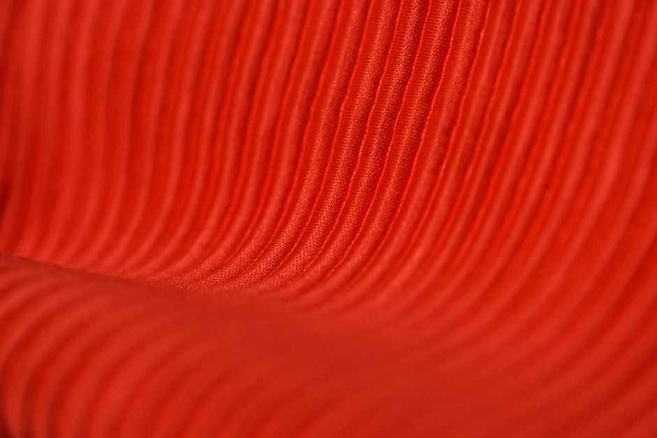 银朱 — Macro view of vibrant red ribbed corduroy textile showing detailed texture.