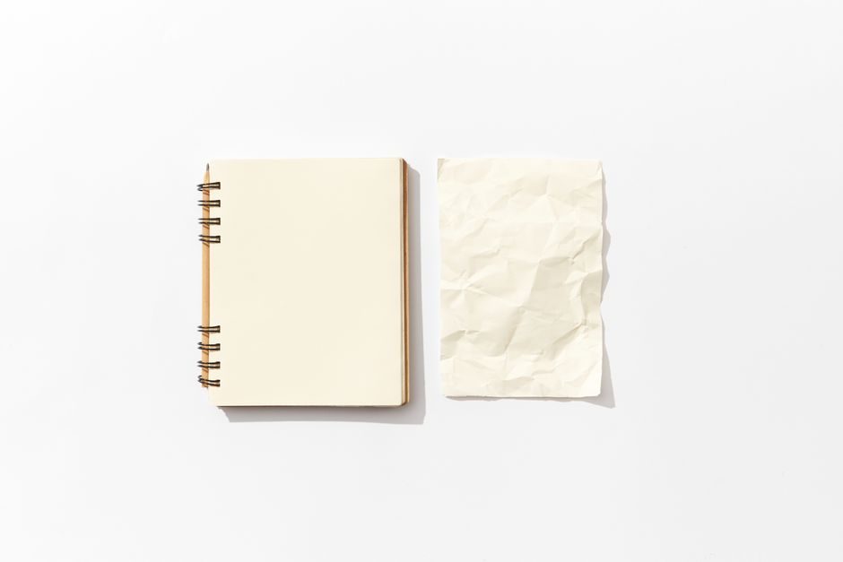 酂白 — Flat lay of an open spiral notebook and a crumpled paper on a white background, perfect for mockup designs.