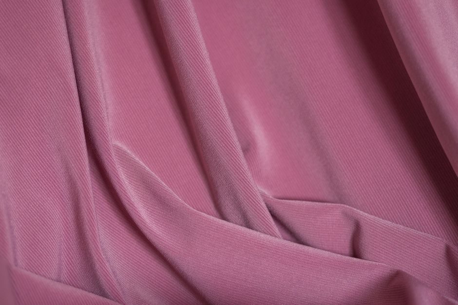 紫茎屏风 — Close-up of pink corduroy fabric showcasing its ruffled and textured surface.